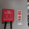 Ultrafire fire blanket in red container mounted on wall with instruction label next to it