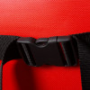 A close-up of a black side‑release buckle attached to a black woven strap on a textured red fabric background.