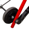 A close-up of a wheel assembly mounted on a red and black metal frame, showing the axle, bolts, and hard rubber wheel.
